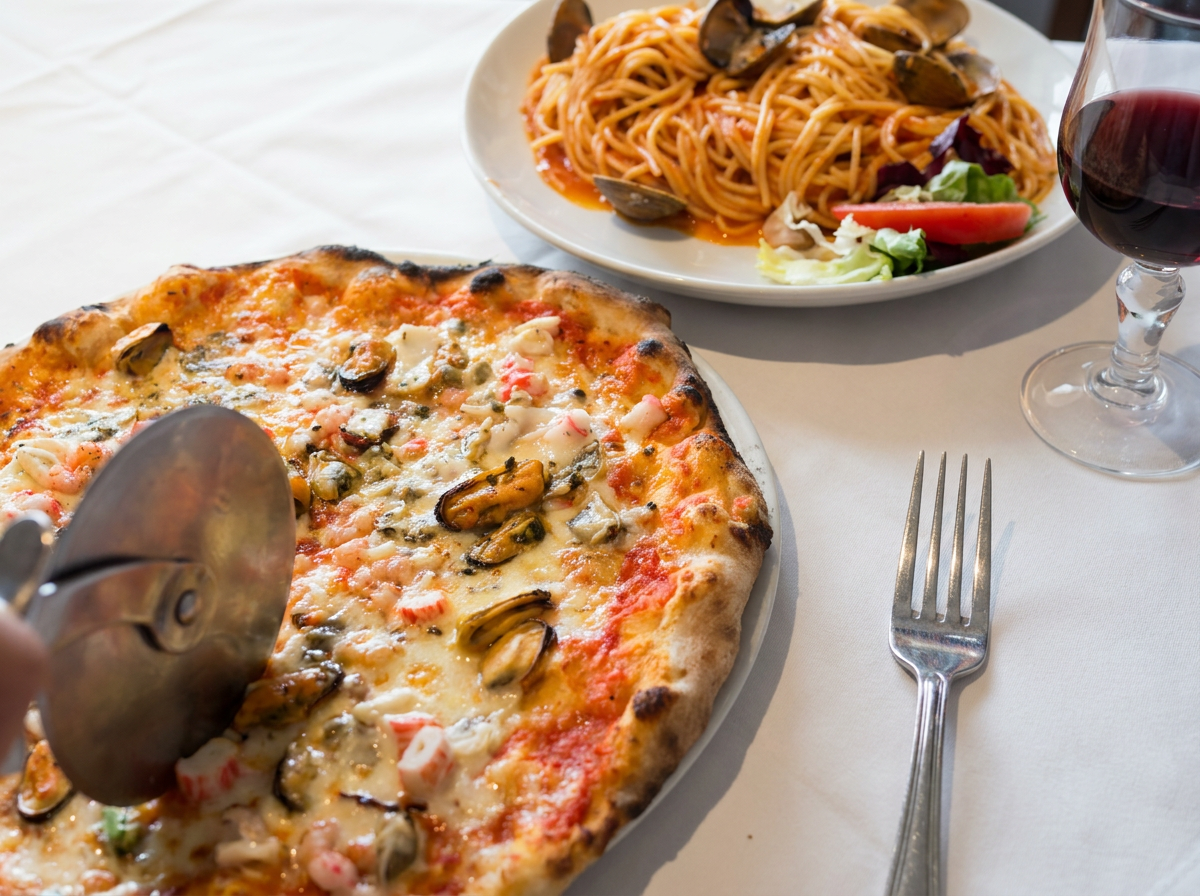 Pizza aux fruits de mer et plat de spaghettis servis avec un verre de vin rouge